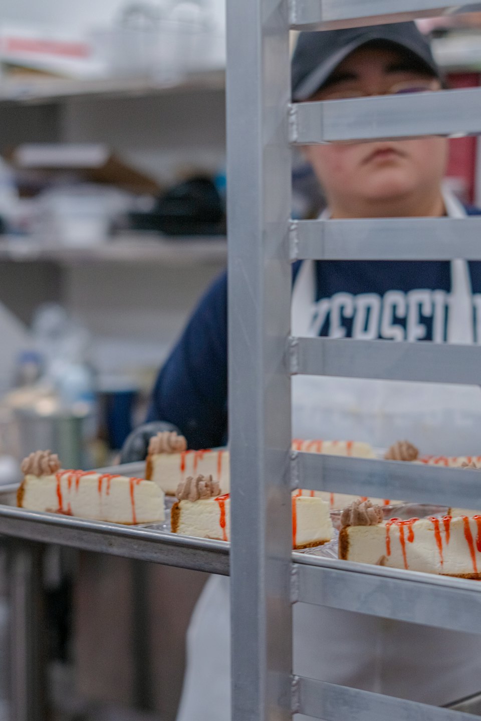Cheesecake slices with red drizzle on metal trays.