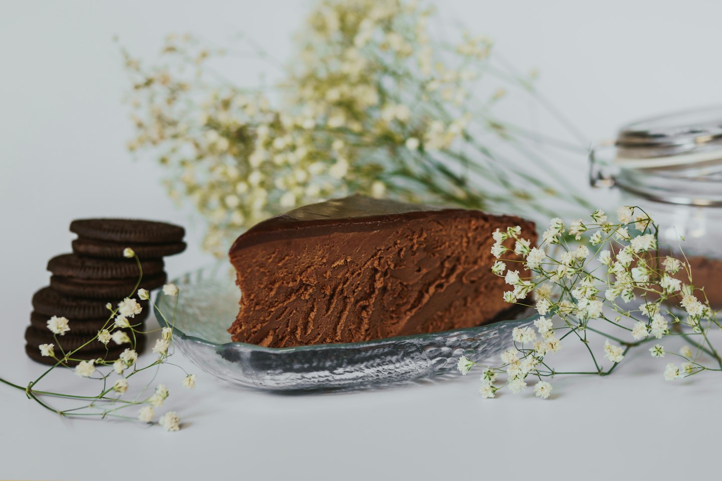 A slice of chocolate cheesecake sits on a glass plate.