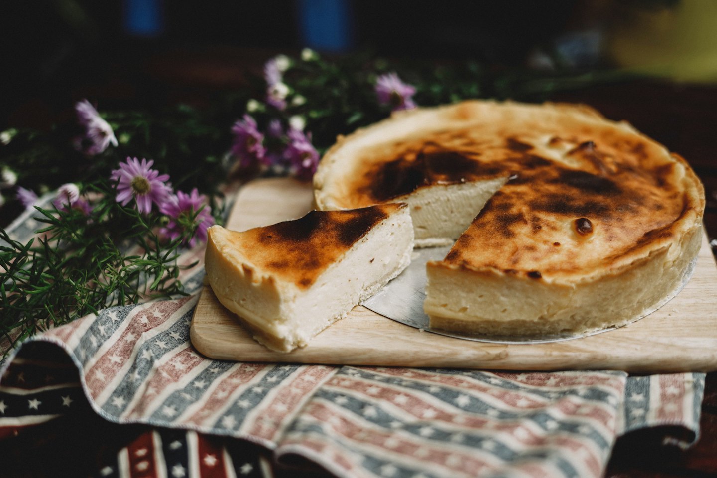 Baked cheesecake with a slice cut out on a wooden board.